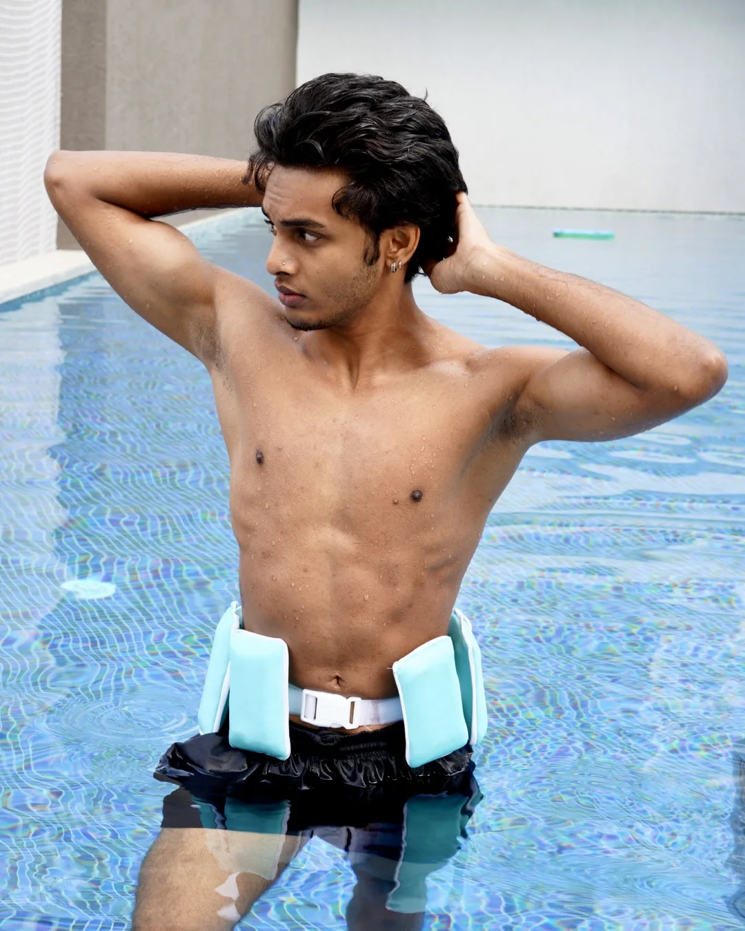 A man standing in the pool wearing the belt, hands behind his head