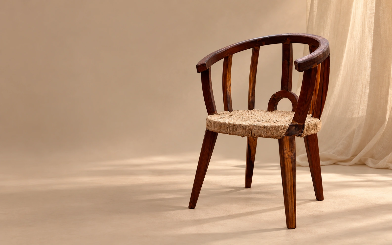 The teak and jute chair Aarohi built, in a warm studio with soft light across the floor