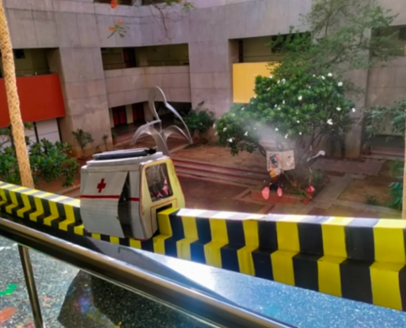 The first physical model of the ambulance, set on a striped barrier in a campus courtyard