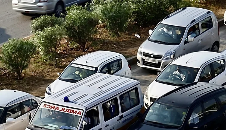 An ambulance boxed in by cars on an Indian road, seen from above