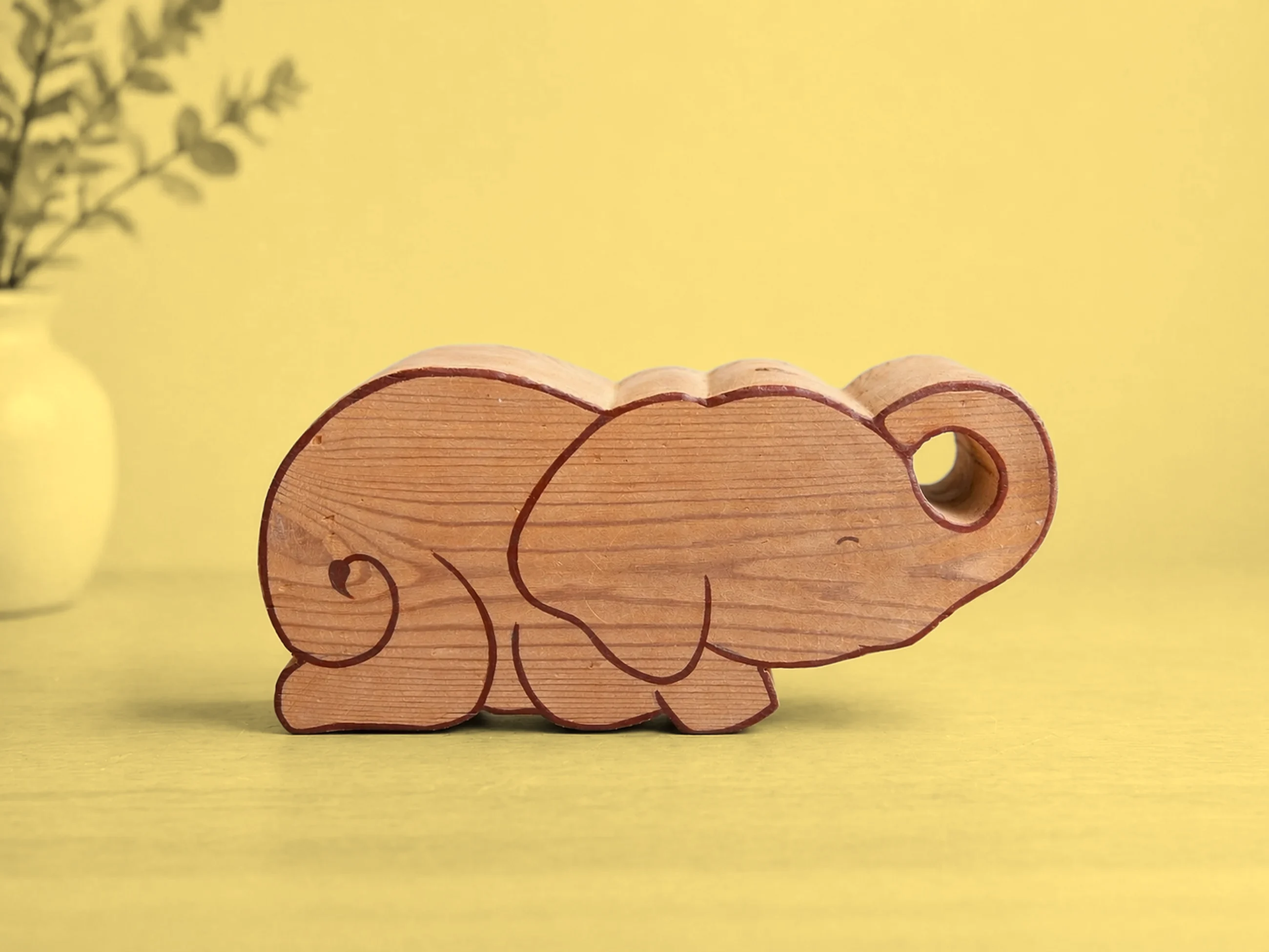 Ellie from the side with no hat: a pine elephant lying down, trunk curled into a loop, eyes closed