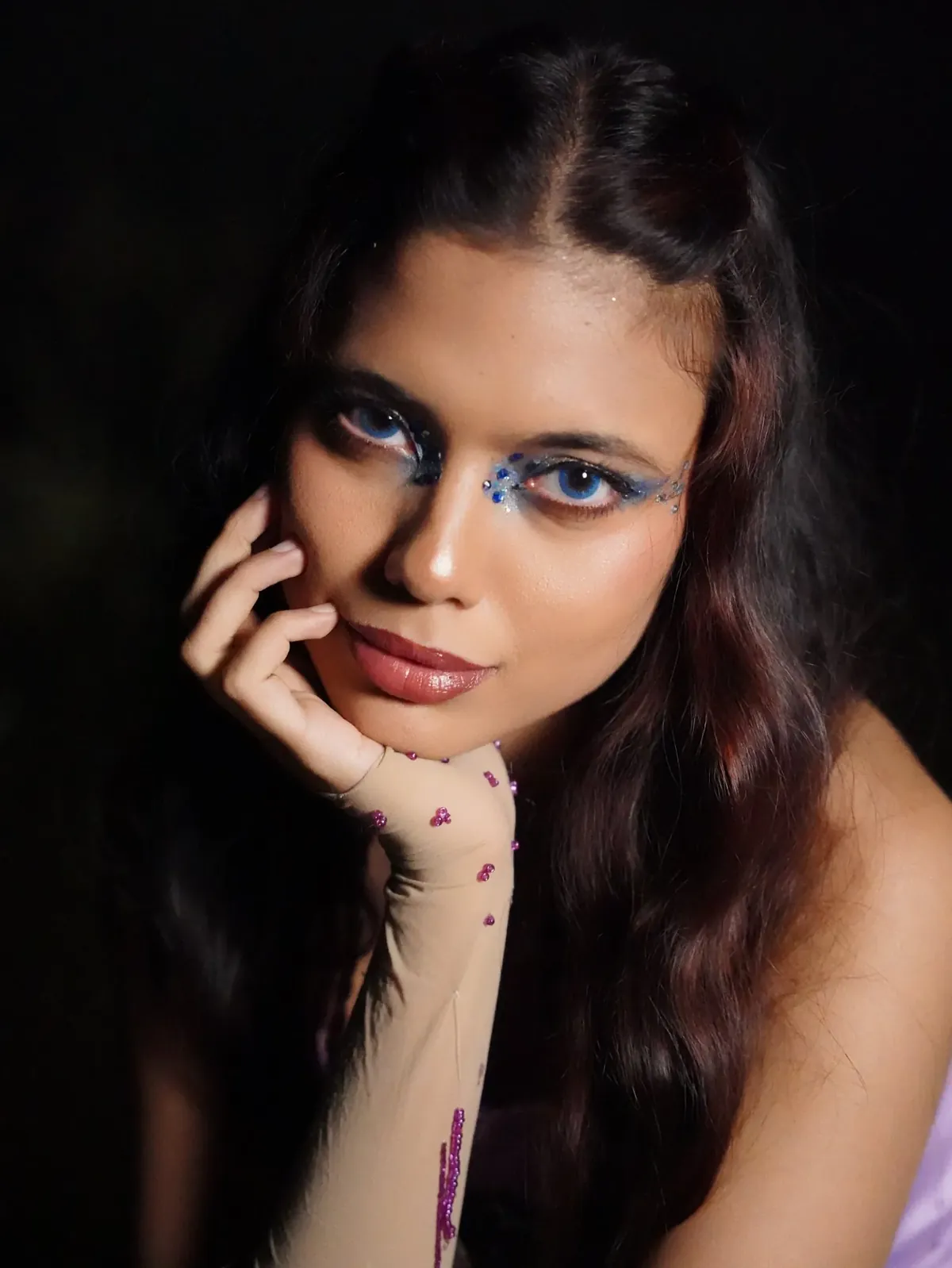 Close portrait with blue crystal eye make-up and a beaded glove
