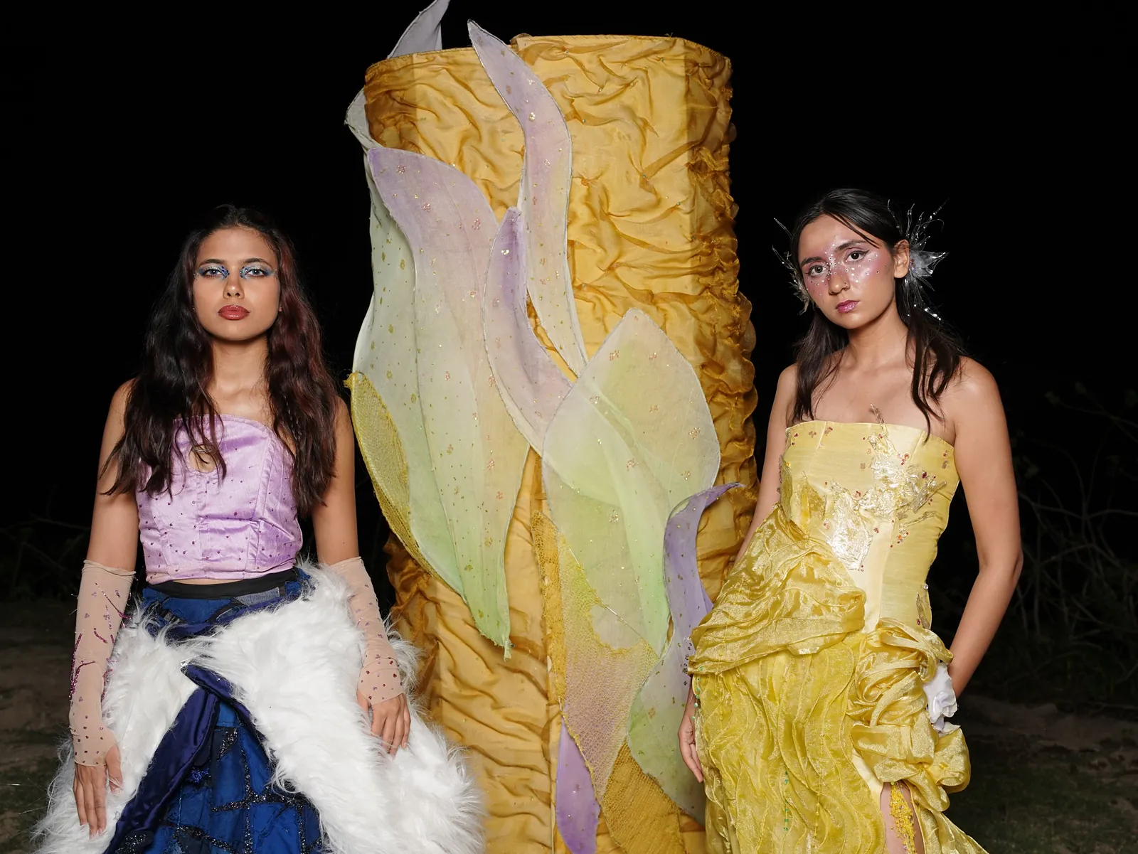 Both models beside the column at night