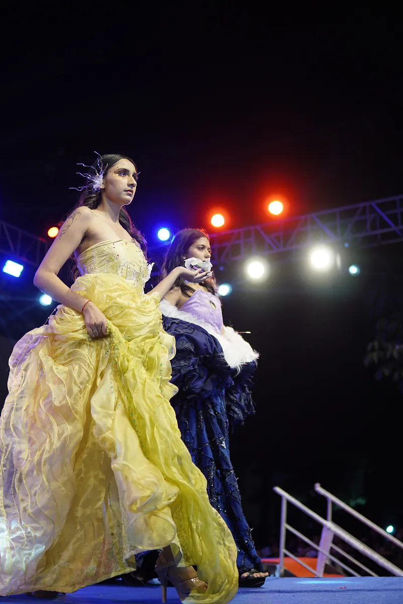 The yellow gown walking forward under red and white lights